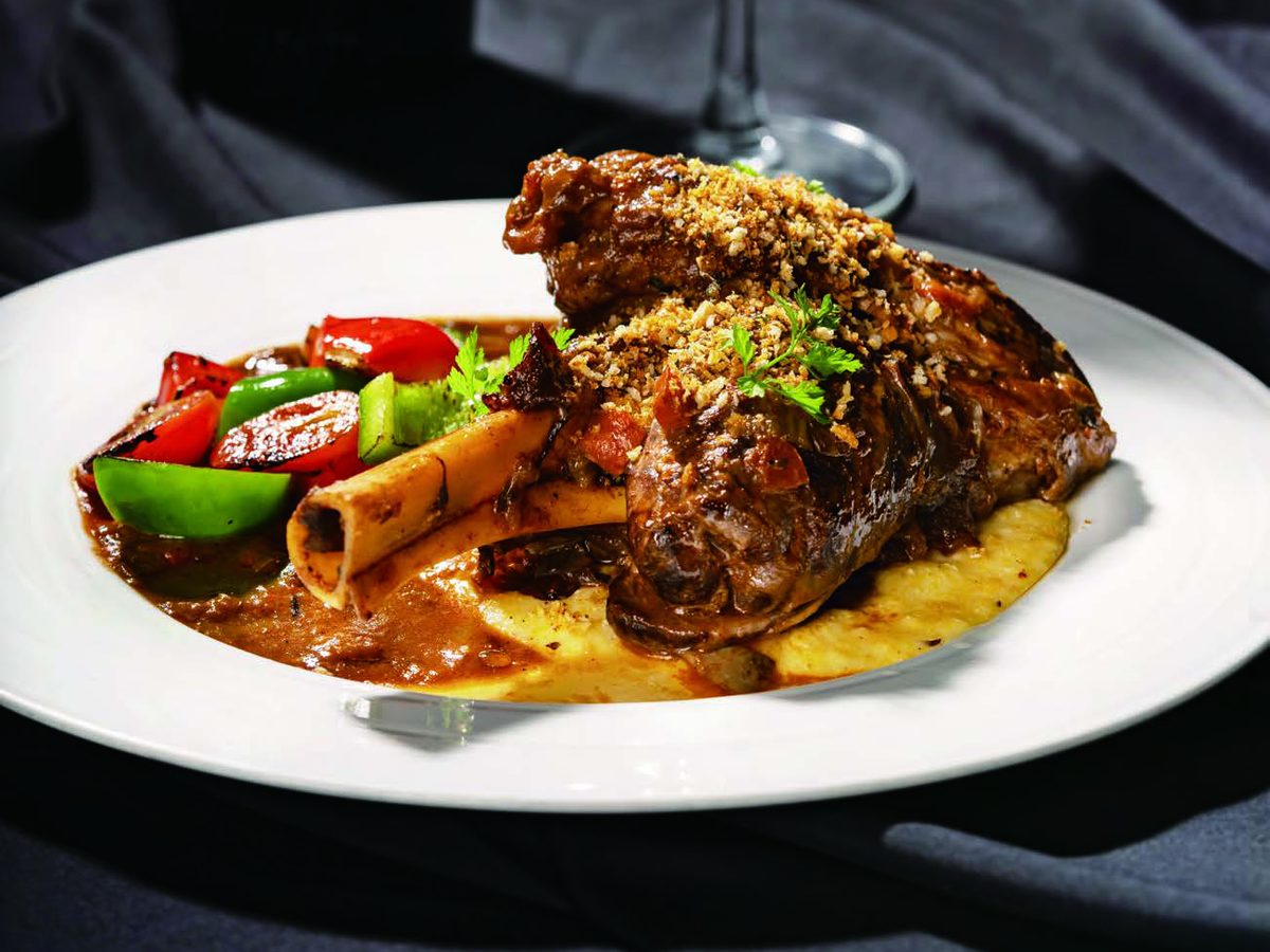 Lamb shank osso buco style with cheese polenta and sautéed bell peppers